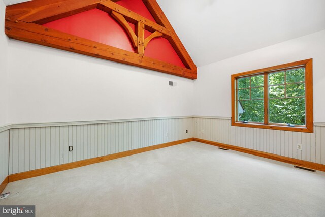 empty room featuring lofted ceiling with beams and carpet floors