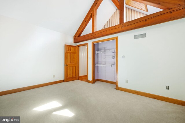 unfurnished bedroom with high vaulted ceiling, beam ceiling, and light carpet