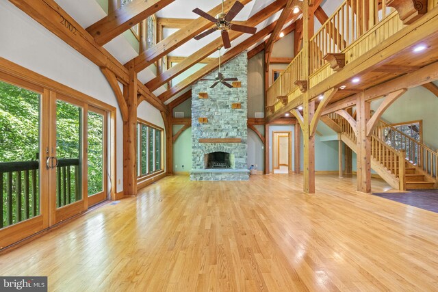 unfurnished living room featuring high vaulted ceiling, ceiling fan, a fireplace, and wood-type flooring