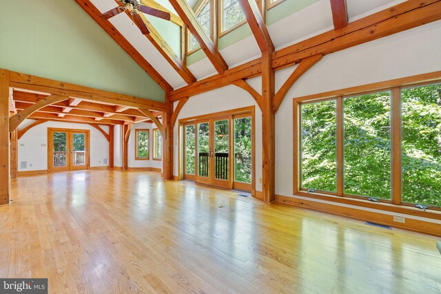 unfurnished living room featuring french doors, light hardwood / wood-style floors, beamed ceiling, ceiling fan, and high vaulted ceiling