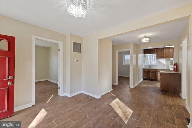 unfurnished living room with dark hardwood / wood-style flooring, a chandelier, and sink