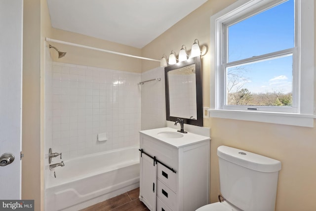 full bathroom with hardwood / wood-style floors, vanity, tiled shower / bath combo, and toilet