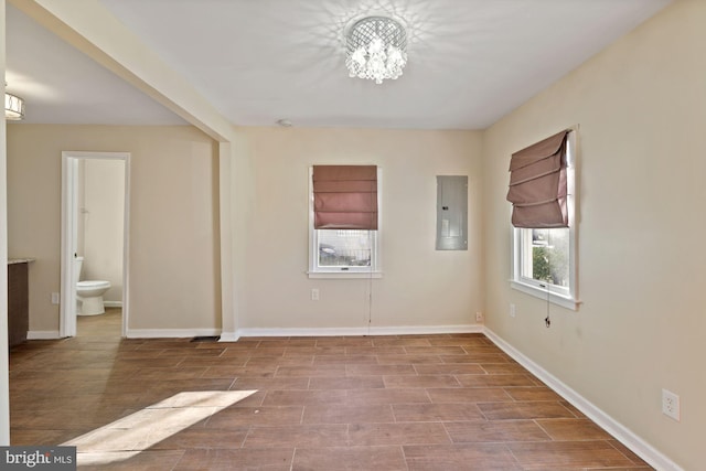 unfurnished room with electric panel, light wood-type flooring, and a chandelier