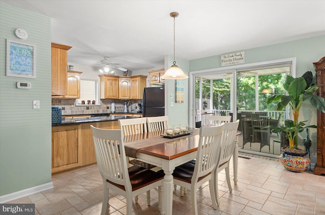 dining space featuring stone tile flooring, baseboards, and a ceiling fan