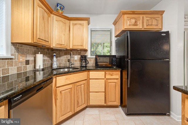 kitchen with light brown cabinetry, dishwasher, decorative backsplash, freestanding refrigerator, and a sink