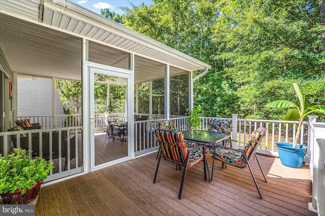 wooden terrace with outdoor dining area and a sunroom