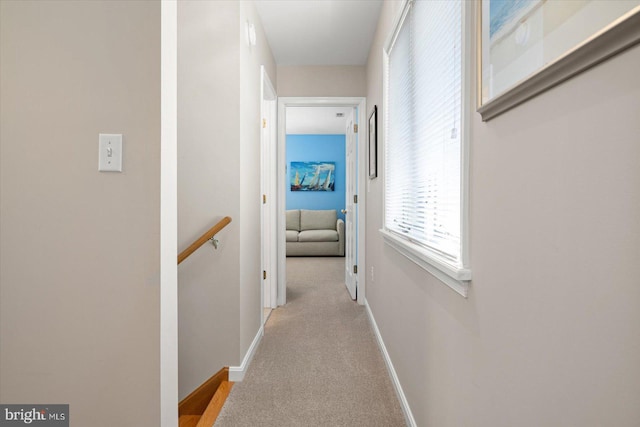 corridor with an upstairs landing, baseboards, and carpet floors