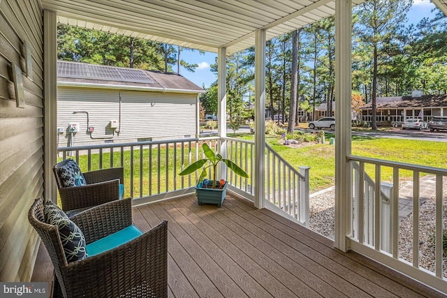 wooden deck with a lawn and covered porch