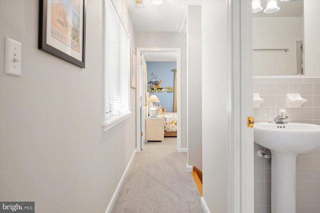 hall featuring tile walls, carpet flooring, and baseboards