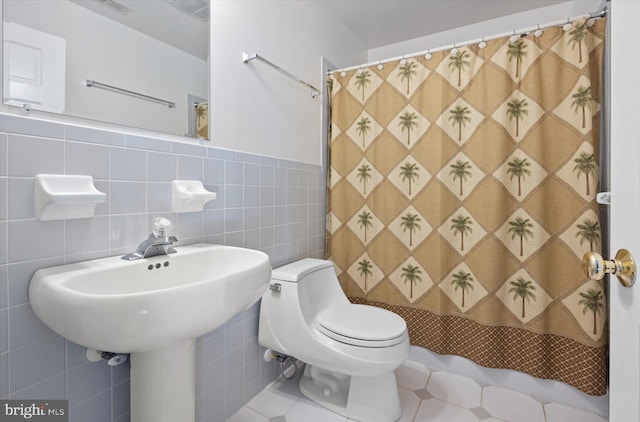 bathroom featuring tile walls, toilet, walk in shower, and tasteful backsplash