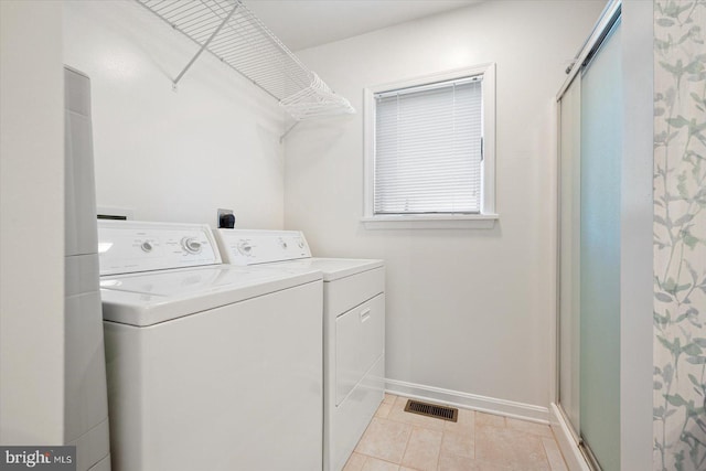 clothes washing area featuring visible vents, light tile patterned floors, baseboards, laundry area, and washing machine and clothes dryer