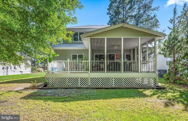 rear view of house featuring a lawn, a sunroom, and a deck