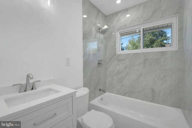 full bathroom featuring tiled shower / bath, vanity, and toilet