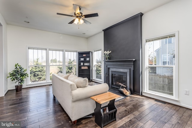 living room with a large fireplace, ceiling fan, and dark hardwood / wood-style flooring