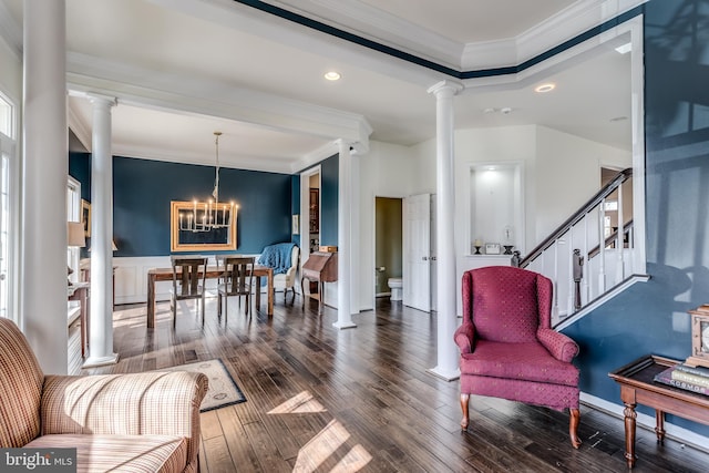 sitting room with dark hardwood / wood-style flooring, an inviting chandelier, crown molding, and ornate columns