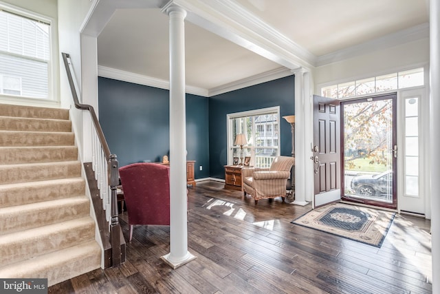 entrance foyer featuring dark hardwood / wood-style flooring, ornamental molding, and ornate columns