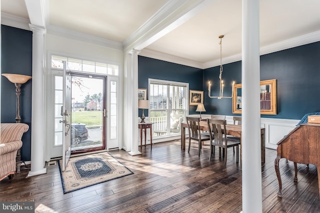 entrance foyer with decorative columns, dark hardwood / wood-style flooring, a notable chandelier, and ornamental molding