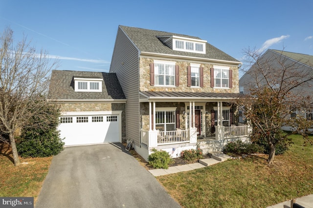 view of front of house with covered porch, a garage, and a front lawn