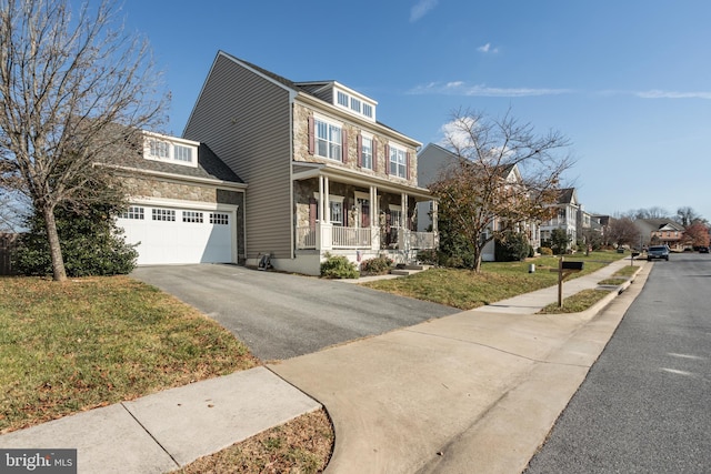 view of property featuring covered porch, a front yard, and a garage