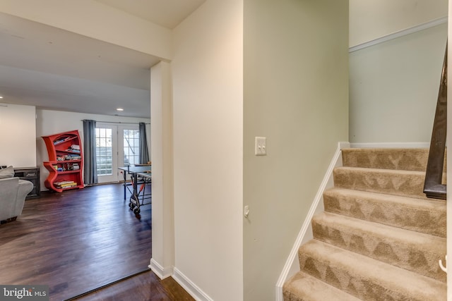 stairway with french doors and hardwood / wood-style flooring