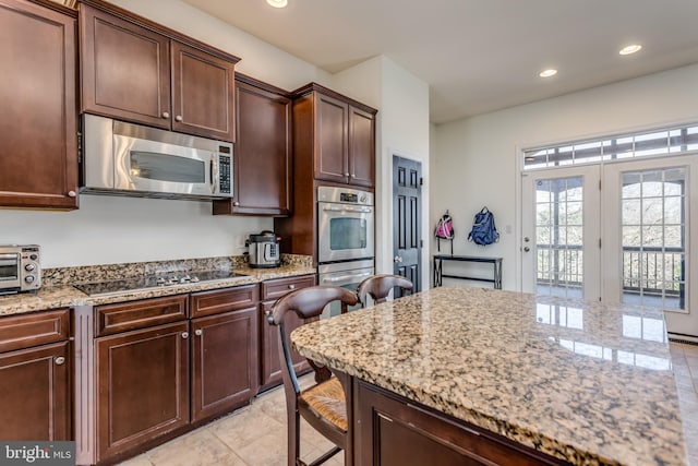 kitchen with black cooktop, light tile patterned floors, and light stone counters