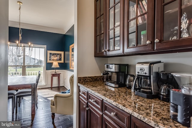 kitchen with pendant lighting, hardwood / wood-style flooring, ornamental molding, light stone counters, and a chandelier