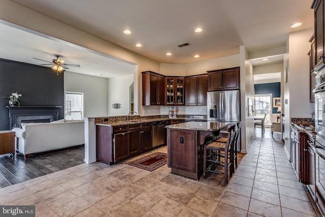 kitchen featuring sink, a center island, a breakfast bar, dark brown cabinets, and appliances with stainless steel finishes