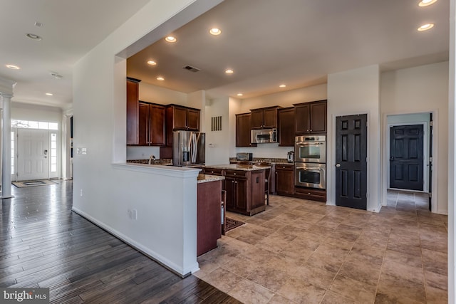 kitchen featuring appliances with stainless steel finishes, a center island, light hardwood / wood-style flooring, and dark brown cabinetry