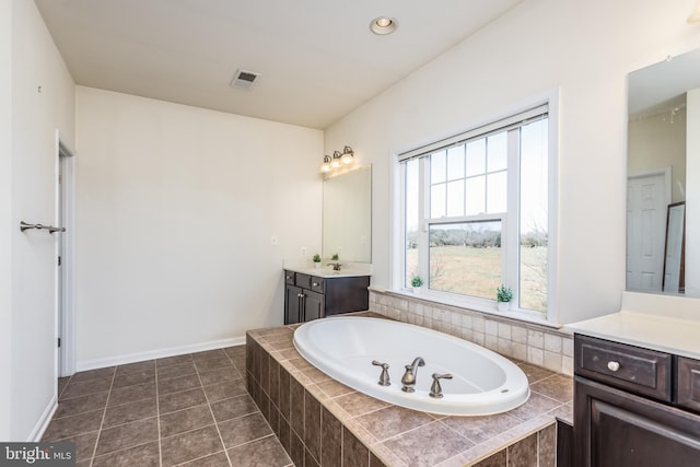 bathroom with vanity, a relaxing tiled tub, and tile patterned floors