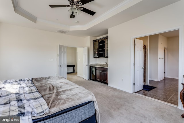 bedroom with carpet, ensuite bath, a raised ceiling, ceiling fan, and crown molding