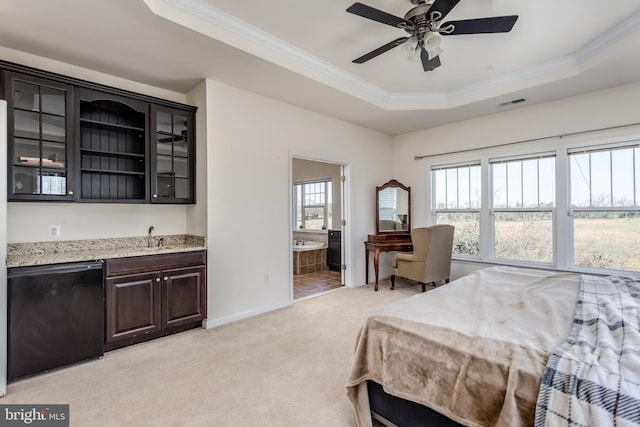 carpeted bedroom with ensuite bath, ceiling fan, a raised ceiling, and multiple windows