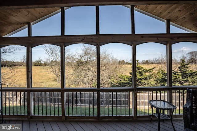 unfurnished sunroom featuring wood ceiling, vaulted ceiling with beams, and a rural view