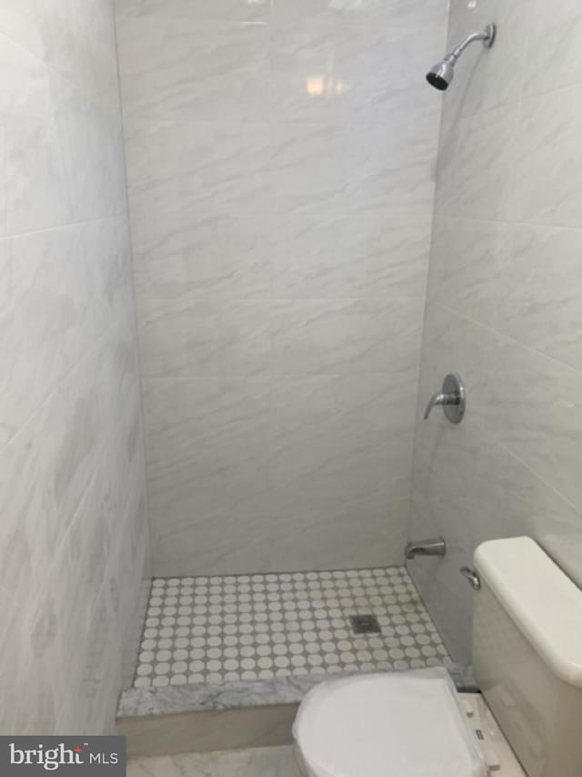 bathroom featuring a tile shower and toilet