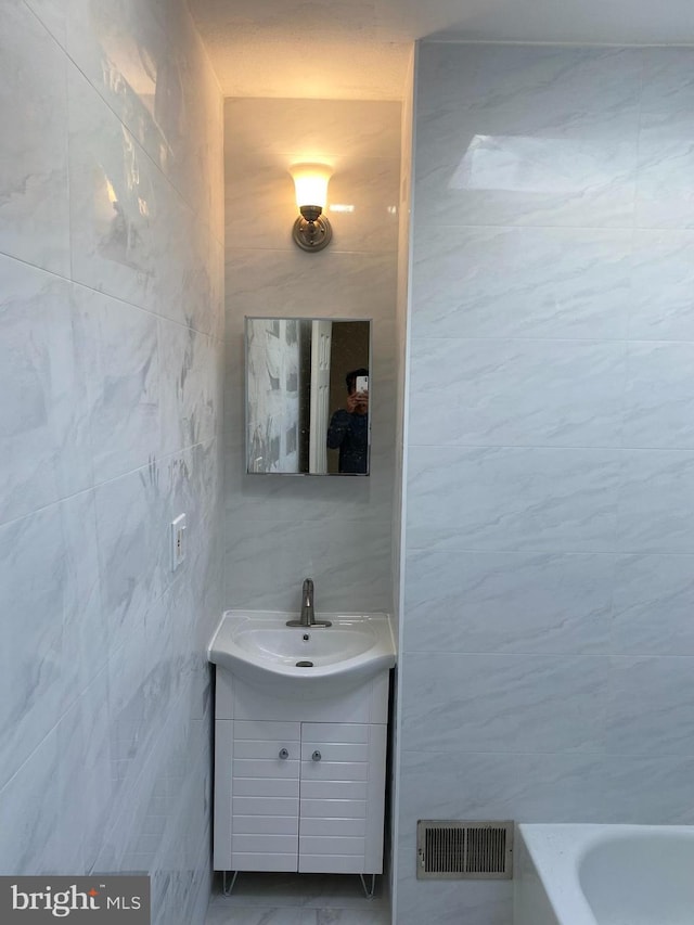 bathroom featuring vanity, tile walls, and a washtub