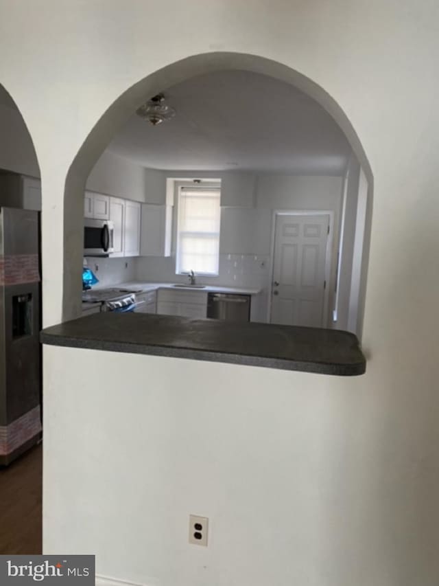 kitchen with stainless steel appliances, white cabinetry, and sink