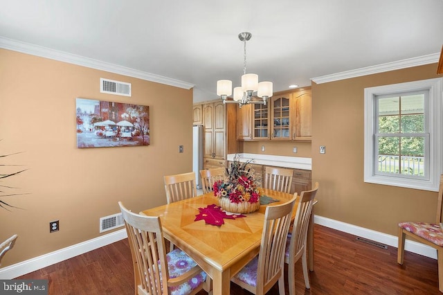 dining area featuring dark wood-type flooring, an inviting chandelier, and crown molding