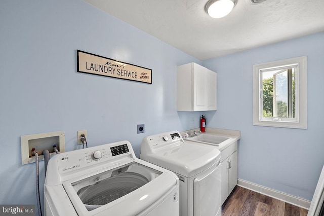 laundry room with cabinets, washer and dryer, sink, and dark hardwood / wood-style floors