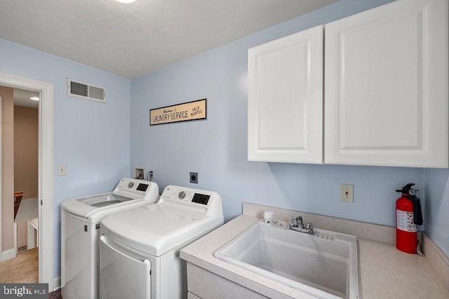 clothes washing area with cabinets, washing machine and clothes dryer, and sink