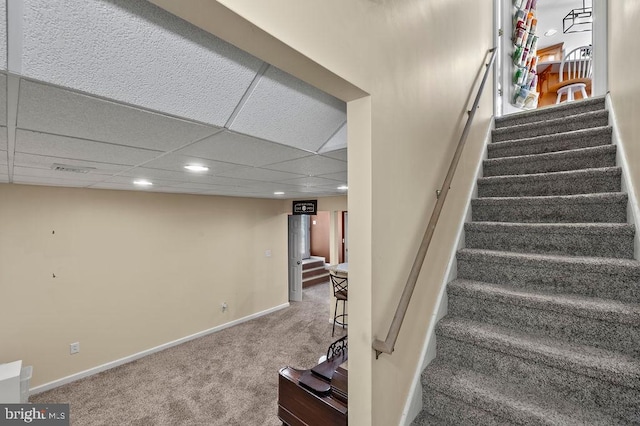 stairs with carpet and a drop ceiling