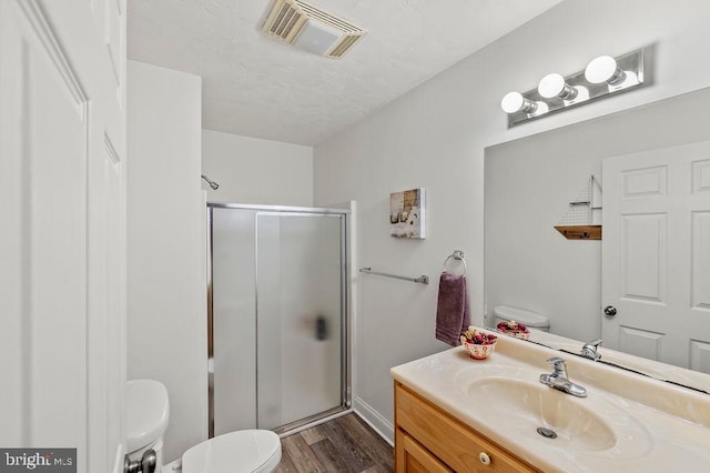 bathroom with vanity, toilet, hardwood / wood-style flooring, and a shower with shower door