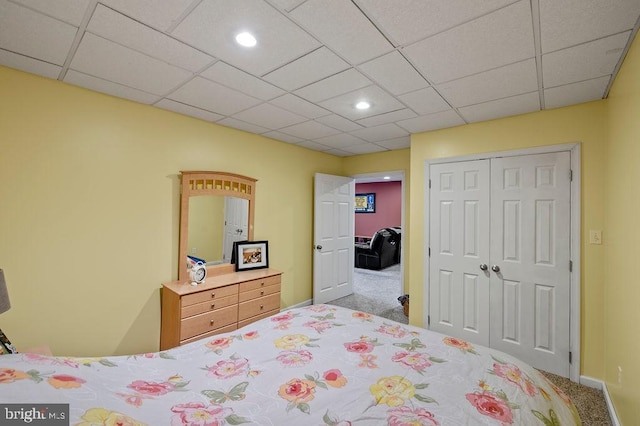 bedroom featuring carpet, a drop ceiling, and a closet