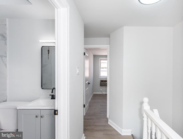 hallway with light wood-type flooring, sink, and a wall mounted AC