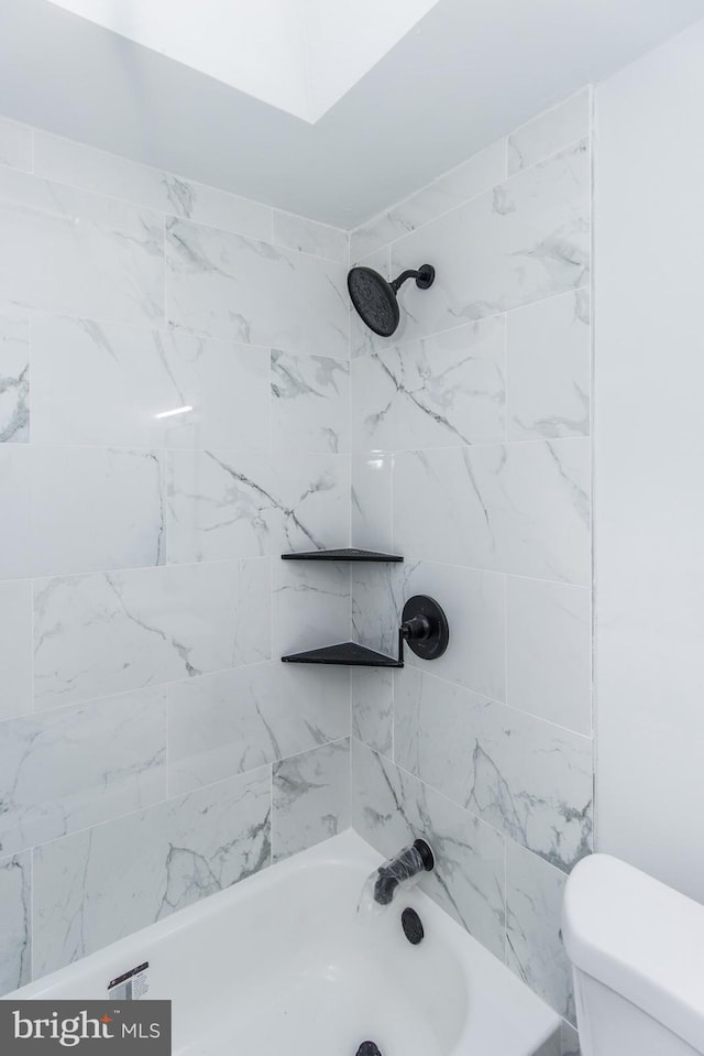 bathroom featuring tiled shower / bath combo and toilet