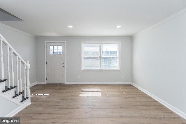 entrance foyer featuring light wood-type flooring, ornamental molding, and plenty of natural light