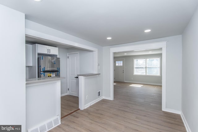 interior space with stainless steel refrigerator, light hardwood / wood-style flooring, and white cabinetry