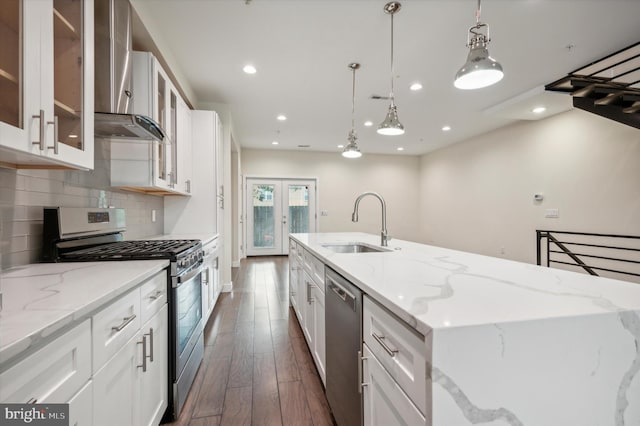 kitchen with light stone counters, white cabinets, sink, dark wood-type flooring, and appliances with stainless steel finishes