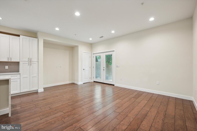 unfurnished living room with hardwood / wood-style floors and french doors