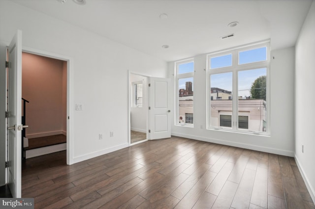 unfurnished bedroom with a spacious closet and dark hardwood / wood-style floors