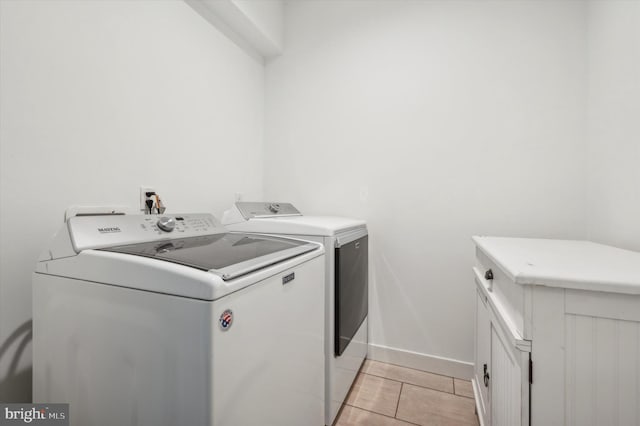 laundry area featuring cabinets, light tile patterned floors, and separate washer and dryer