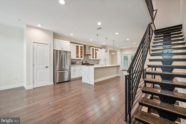 kitchen featuring appliances with stainless steel finishes, hanging light fixtures, white cabinetry, and a center island